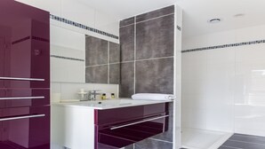 A modern bathroom with a vanity, a mirror, and a shower area.