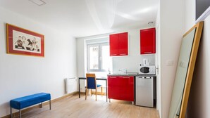 A compact kitchen with red cabinets, a microwave, and a bench.