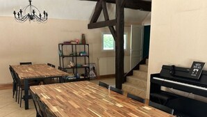 A dining area with wooden tables and chairs, a piano, and a bookshelf. - L'Hydromel, estate with swimming pool 1h30 from Paris (Auvilliers-en-Gâtinais)