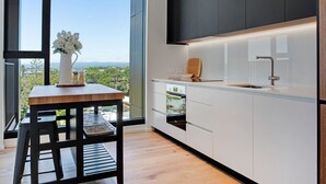 Een moderne keuken met een groot raam, een houten tafel met een vaas en uitzicht op de omgeving.