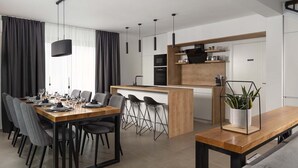 A modern kitchen with a central island, a dining area with a long table and chairs, and a living area with a sofa and a coffee table. - Villa Adria in Valbandon (Valbandon)