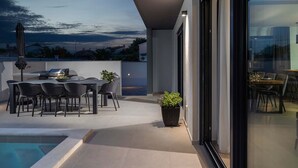 A modern outdoor patio with a pool, dining area, and grilling station. - Villa Adria in Valbandon (Valbandon)