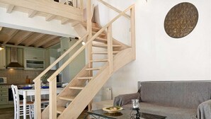Un vaste espace de vie comprenant un escalier en bois, une table à manger avec des chaises, un canapé et une table d’échecs.