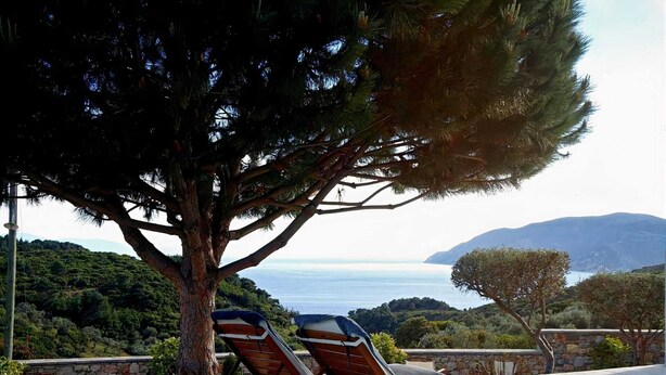 Un espace piscine avec des chaises longues et une vue sur la mer et les collines.