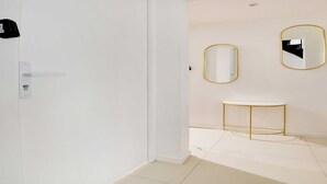 A modern hotel room with a white door, a small console table, and two wall-mounted mirrors with gold frames. - Cosy Studio for 2P with A/C - Near Montmartre (Paris)