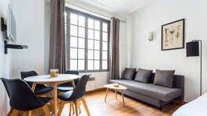 A modern room with a dining table, chairs, a sofa, and a bed. - Cosy Studio - 4P - Palais des Congres (Paris)