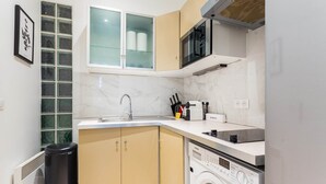 A compact kitchen with a built-in washing machine, a microwave, and a sink. - Cosy Studio - 4P - Palais des Congres (Paris)