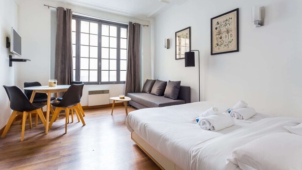 A hotel room with a bed, a sofa, a dining table with chairs, a TV, and artwork on the walls. - Cosy Studio - 4P - Palais des Congres (Paris)