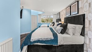 A modern bedroom with a large bed, a view to the outside, and a patterned wall.