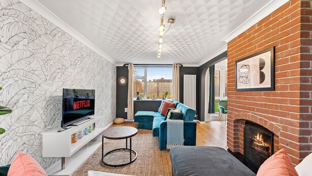 A living room with a TV, sofa, fireplace, and patterned wallpaper. - Boutique Cambridgeshire Gem (Cambridge)