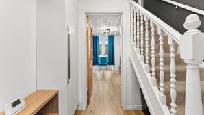 A hallway with a wooden floor, white walls, a white railing, and a blue chair in the distance. - Boutique Cambridgeshire Gem (Cambridge)