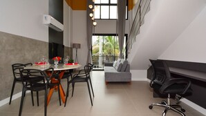 A modern dining area with a round table, black chairs, and a grey sofa. - Sunset Lagoa - LDI002 (Florianópolis)