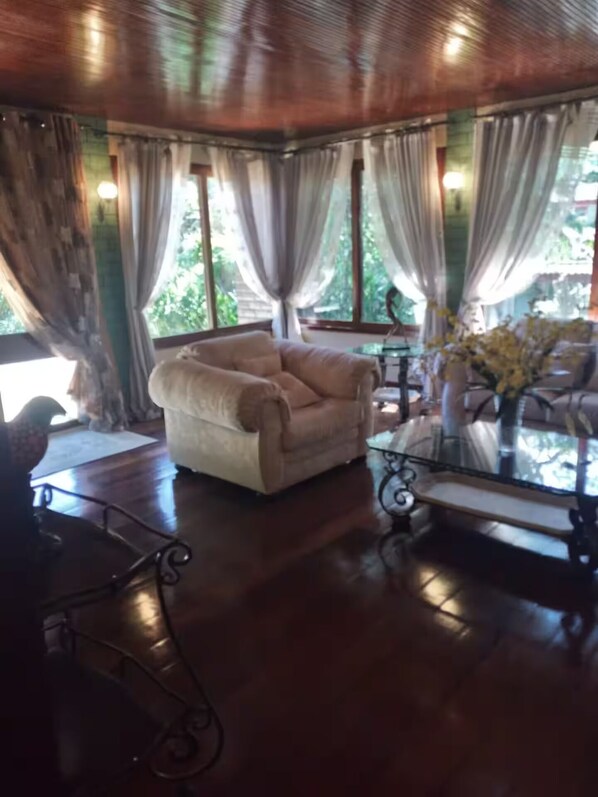 A cozy room with a plush armchair, a glass coffee table, and a vase of flowers.