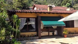 Une maison avec un toit en tuiles, un auvent vert et une terrasse avec une chaise.