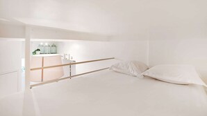 A minimalist bedroom with a bed, a bedside table, and a small window. - Charming studio - 2P- Le Marais (Paris)