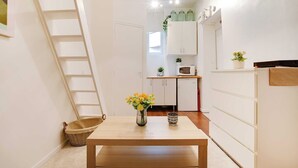A narrow kitchen with white cabinets, a wooden table, and a small countertop. - Charming studio - 2P- Le Marais (Paris)