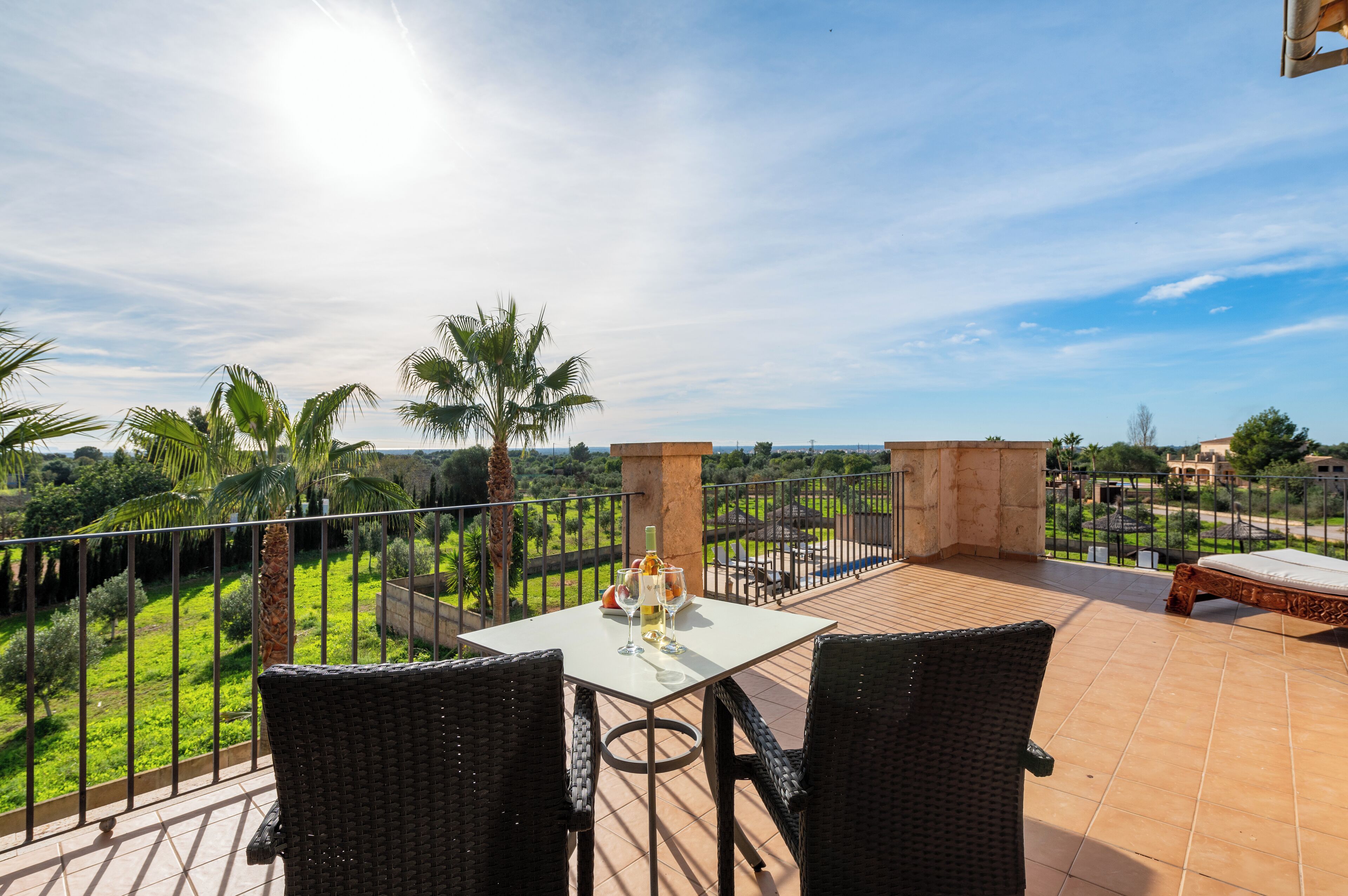Une terrasse avec une table dressée pour deux personnes, offrant une vue sur un paysage luxuriant.