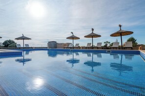Ein Pool mit Liegestühlen und Sonnenschirmen, umgeben von Gebäuden.