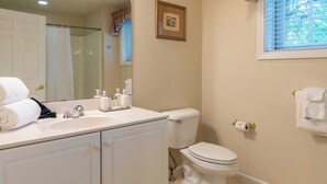 A bathroom with a white sink, mirror, toilet, and window with blinds. - Charming townhome in brilliant Bethel, close to Sunday River. (Bethel)