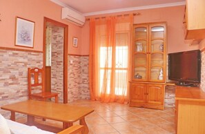 A living room with a wooden table, a TV, and a cabinet with glass doors. - Apartamento Manolete (Conil de la Frontera)