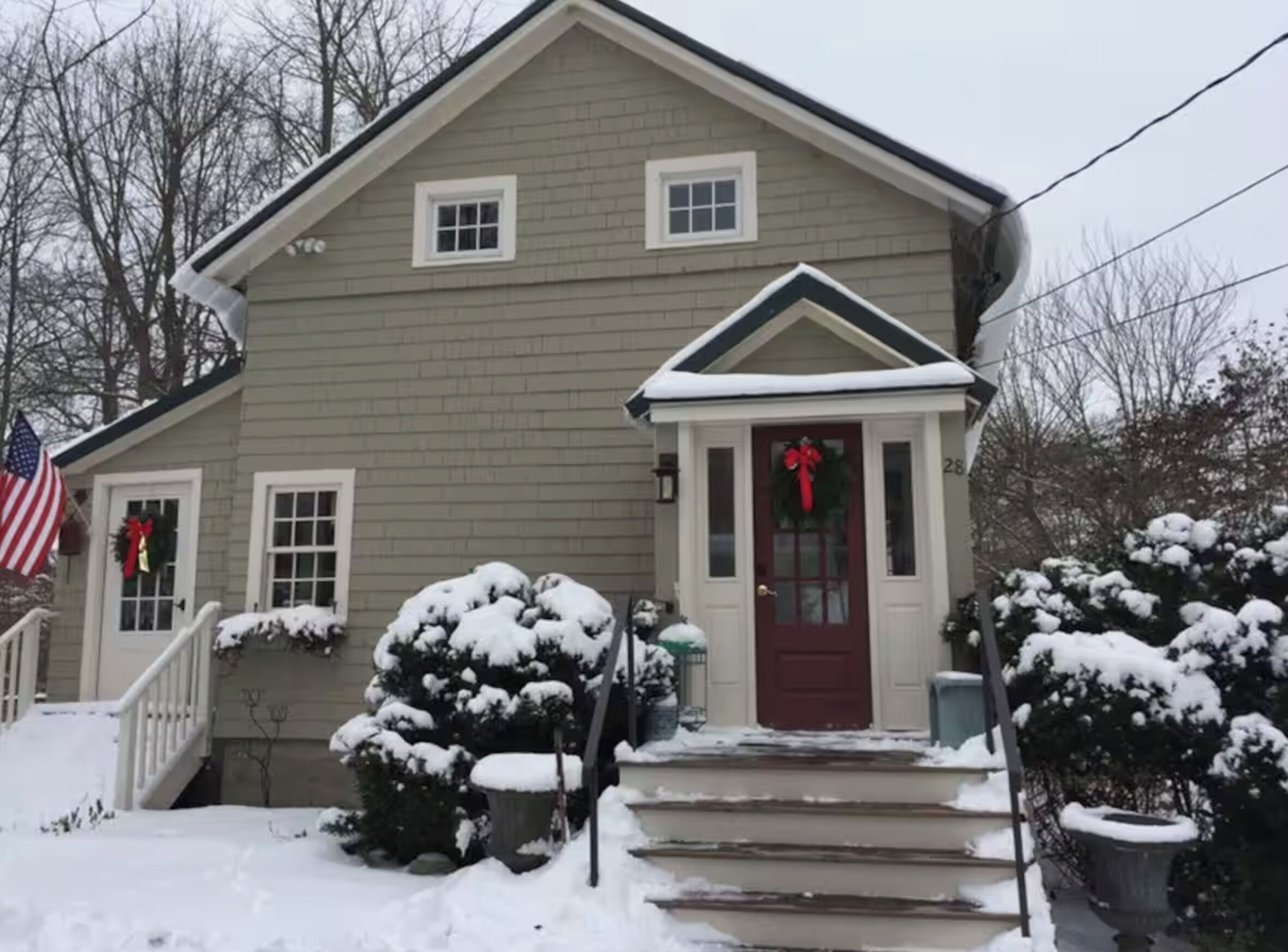 A two-story house with a red front door, a small porch, and a mailbox.