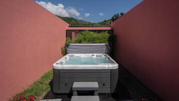 A hot tub in a red-walled outdoor area with a view of mountains in the background.