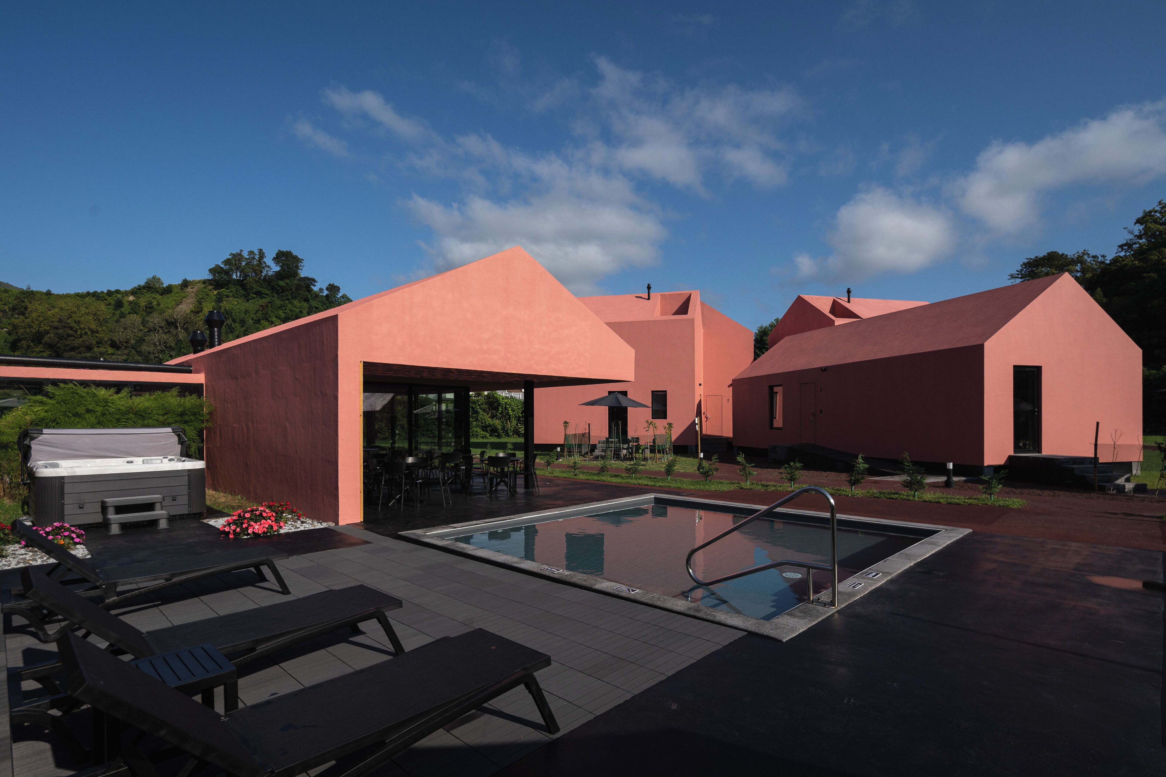 A modern outdoor pool area with lounge chairs, a hot tub, and a barbecue grill.