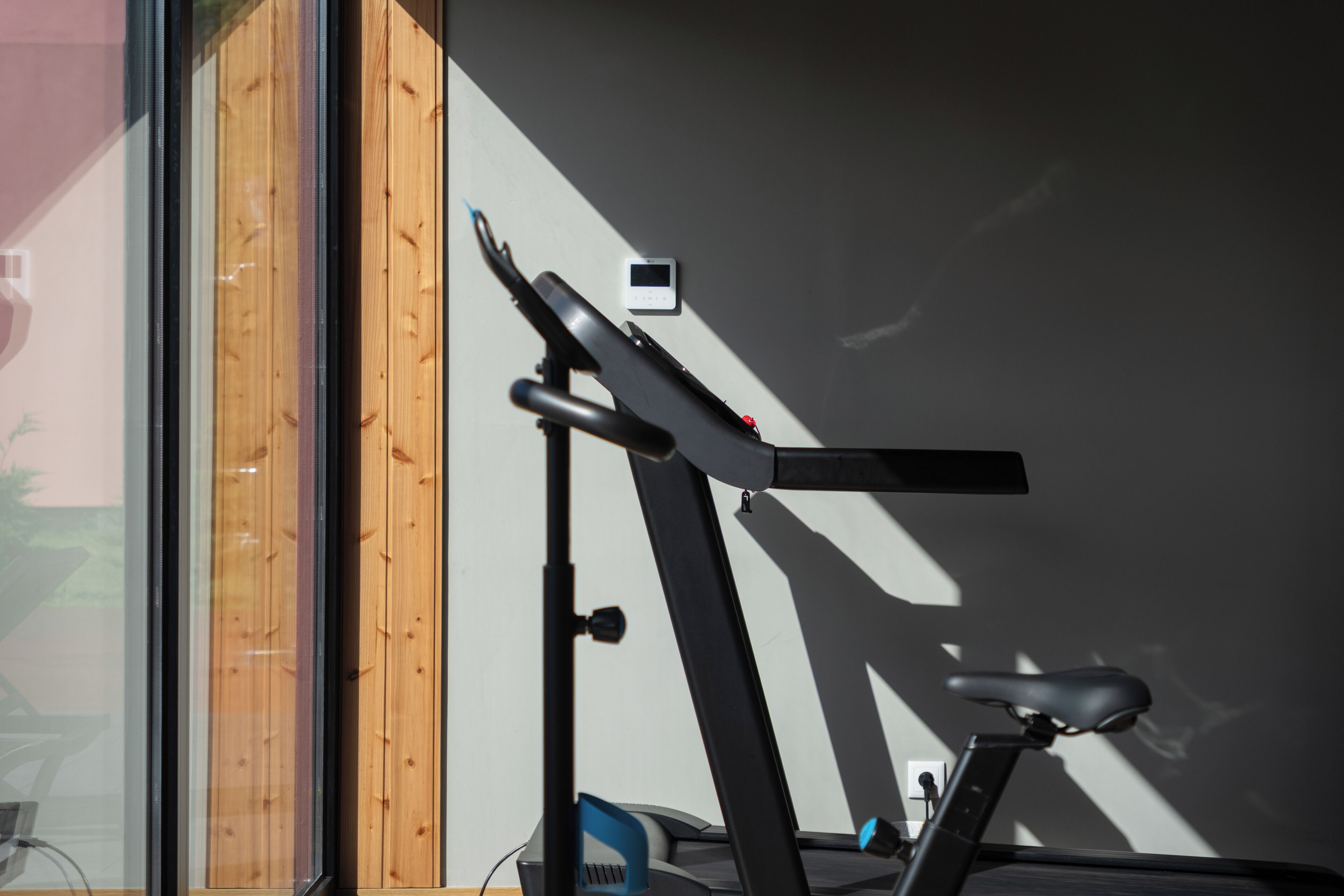 Una bicicleta estatica en una habitació amb una paret de fusta i una finestra.