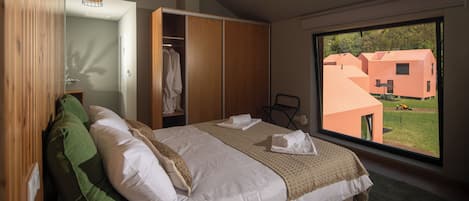 Ein modernes Schlafzimmer mit einem großen Bett, einem Kleiderschrank und Blick auf ein Gebäude.