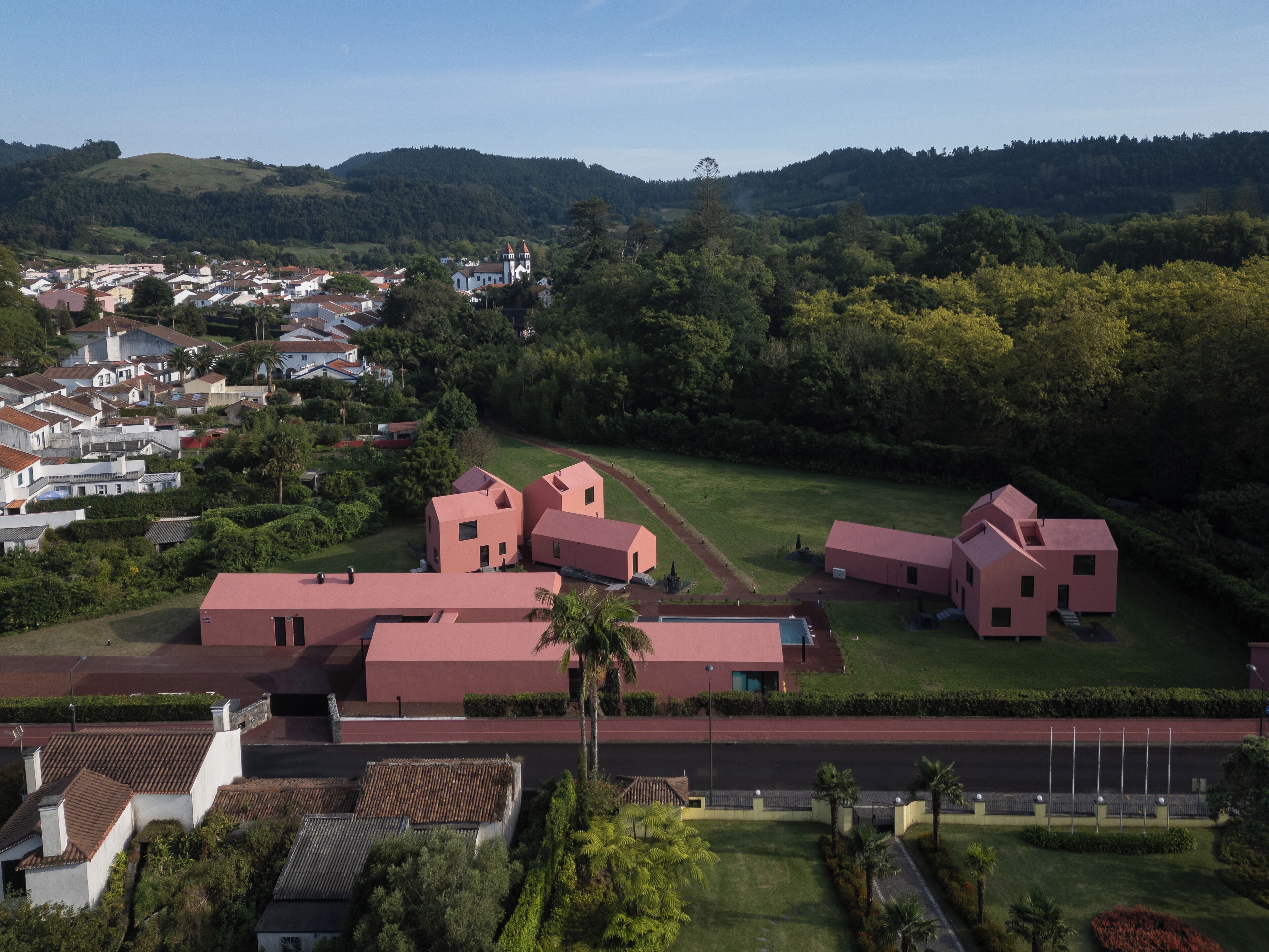 A residential area with modern houses, a church, and a hilly landscape in the background.