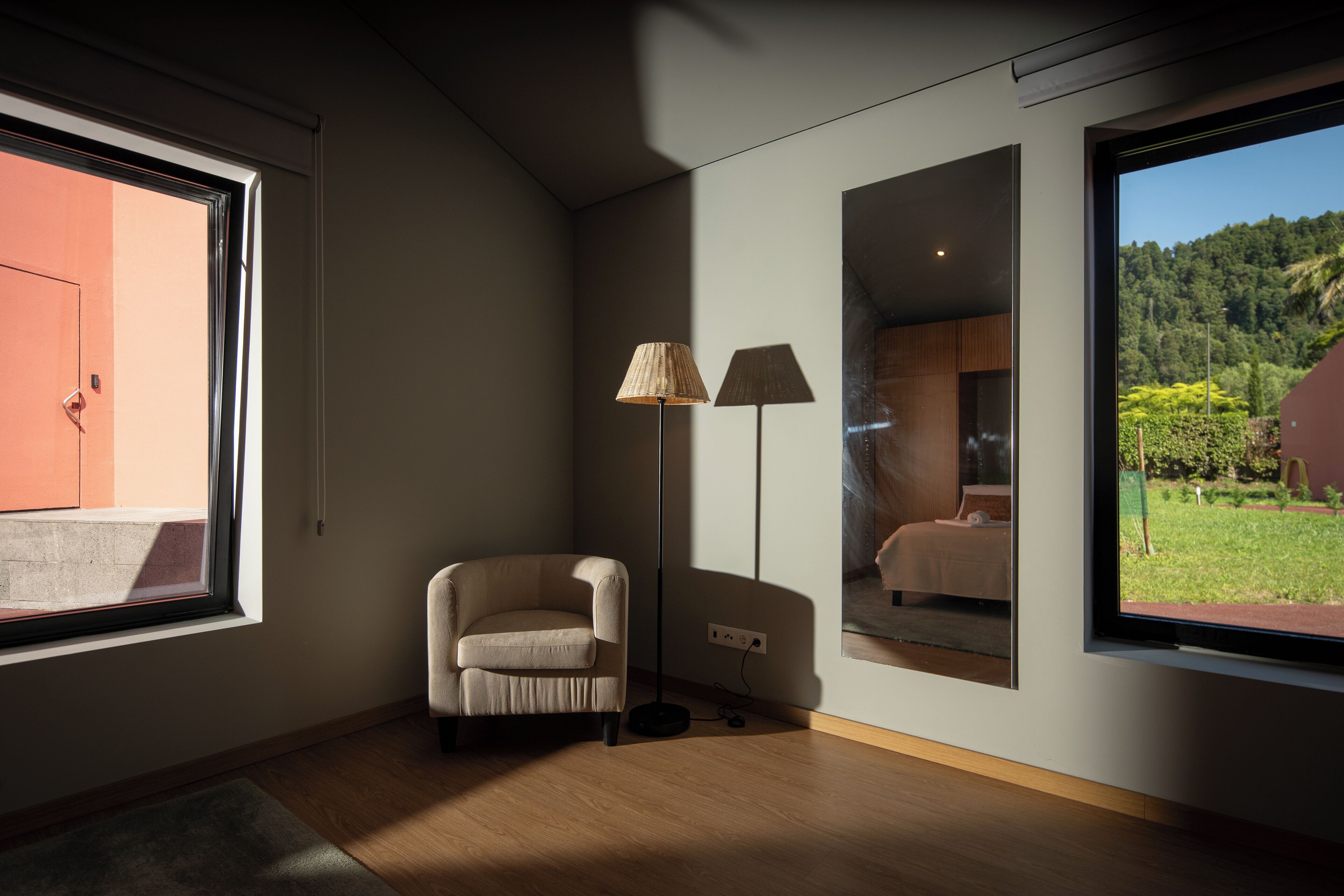 Una habitación moderna con un ventanal grande, una lámpara de pie y una silla.