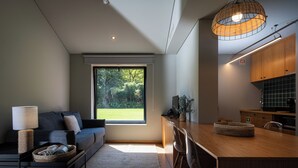 A modern living room with a sofa, a coffee table, and a dining area with a wooden table and chairs. - Canto's Green Garden & SPA  (Povoacao)