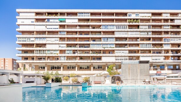 Un hotel de varios pisos con una piscina en primer plano.