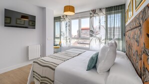 Un dormitorio con cama, un radiador, una ventana con cortinas y una lámpara colgante.