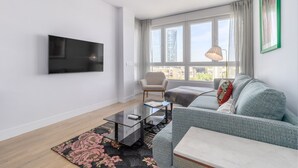 Una sala de estar moderna con un televisor de pantalla plana, un sofá, un sillón y una mesa de centro.