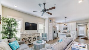 A modern living room with a sofa, a coffee table, a television, and a ceiling fan.