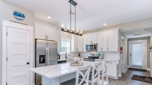 A modern kitchen with white cabinetry, stainless steel appliances, and a central island with seating.