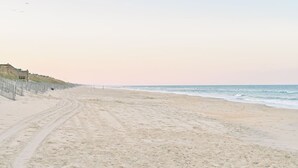 A sandy beach with a fence and a building on the left.