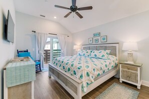A bedroom with a bed, a ceiling fan, a TV, a nightstand, and a window with curtains.