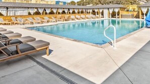 A pool area with lounge chairs, a pool, and a covered seating area.