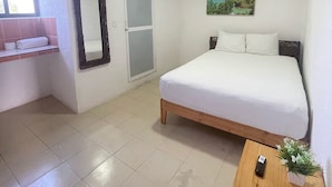 Ein Schlafzimmer mit einem Bett, einem Nachttisch aus Holz, einem Spiegel, einer Tür und einem Fenster.