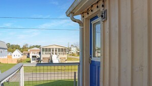 A residential property with a blue door, a balcony with a metal railing, and a view of neighboring houses and a covered structure. - Off The Hook (Port St. Joe)
