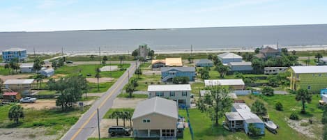 A coastal residential area with houses, a road, and a view of the ocean.