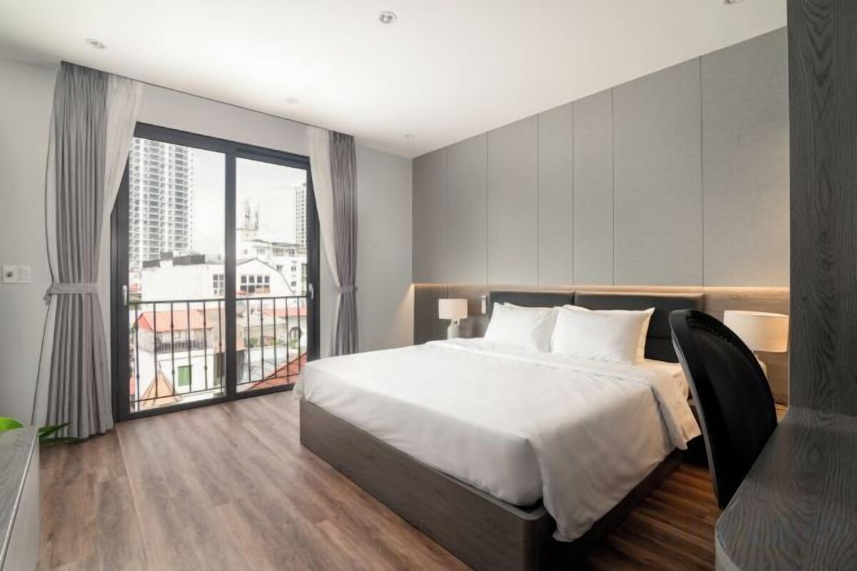Une chambre d’hôtel avec un grand lit, un balcon avec des rideaux et une vue sur la ville.