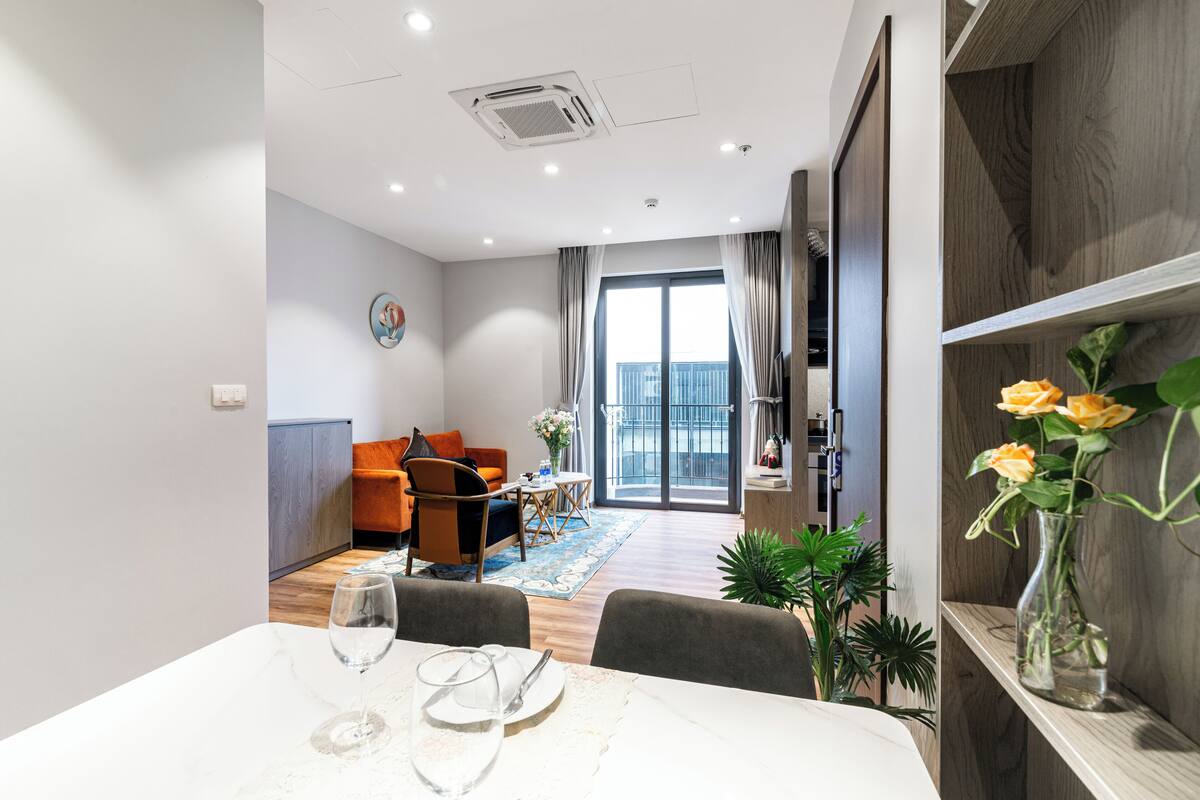 A modern living room with a sofa, dining table, and a balcony with a view.