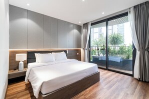 A modern hotel room with a large bed, a nightstand, a lamp, and a view of the outdoors through a sliding glass door. - Luxe Paradise Suites To Ngoc Van (Hanoi)