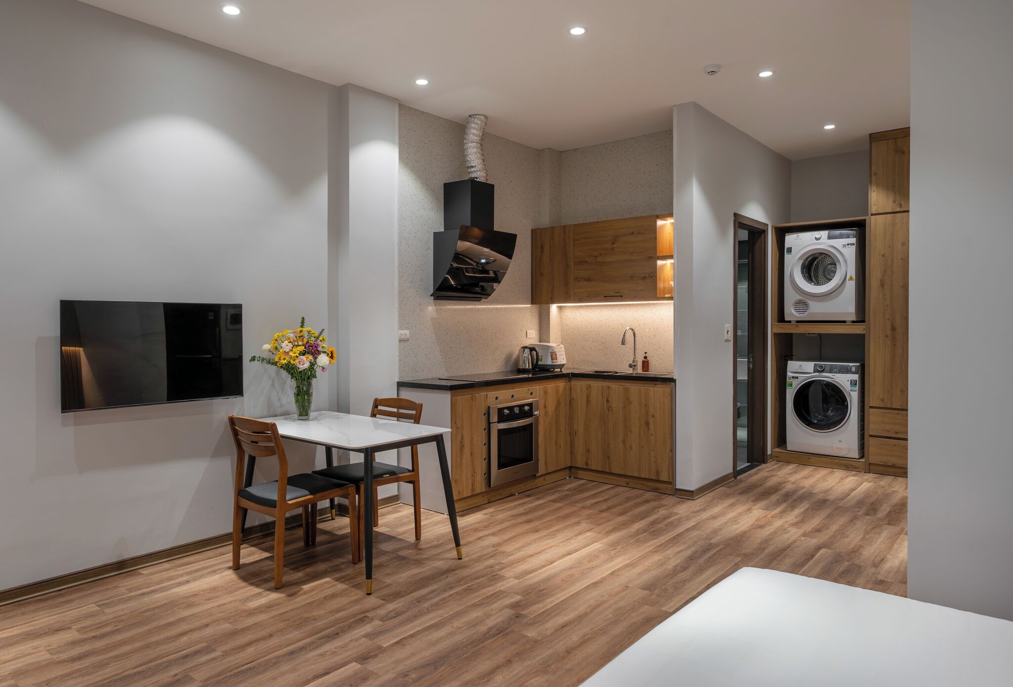 A modern kitchen with wooden cabinets, a built-in oven, a sink, and a washing machine.