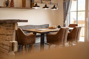 A dining area with a wooden table, four brown chairs, a bench, and pendant lights. - Premium Ferienhaus # 1B mit Sauna (Uttendorf)