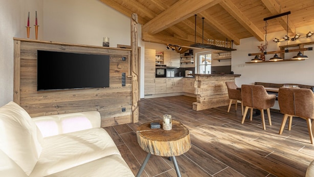 Una cocina moderna con armarios de madera, una isla central y un comedor con una mesa redonda y sillas de madera.