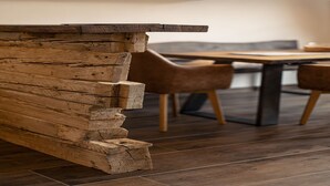 Una mesa de comedor de madera con sillas, un banco de madera y una lámpara colgante en un interior moderno.